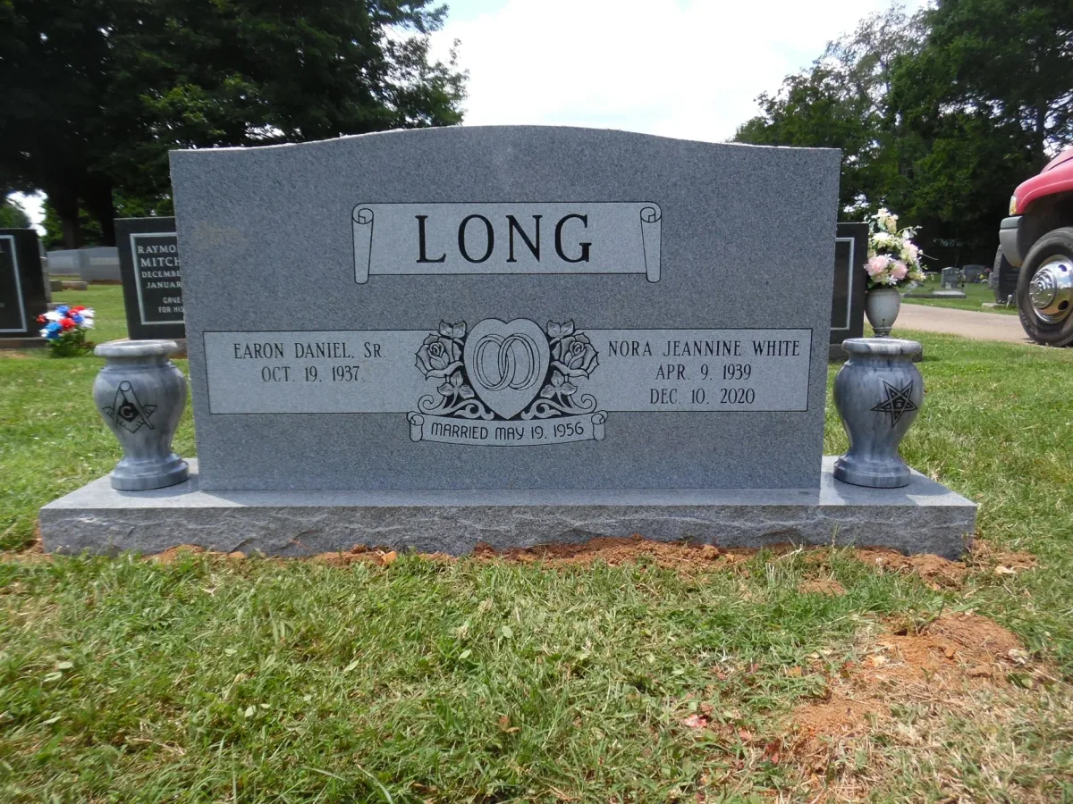 A companion granite memorial with a gently curved top, carved roses and two matching vases