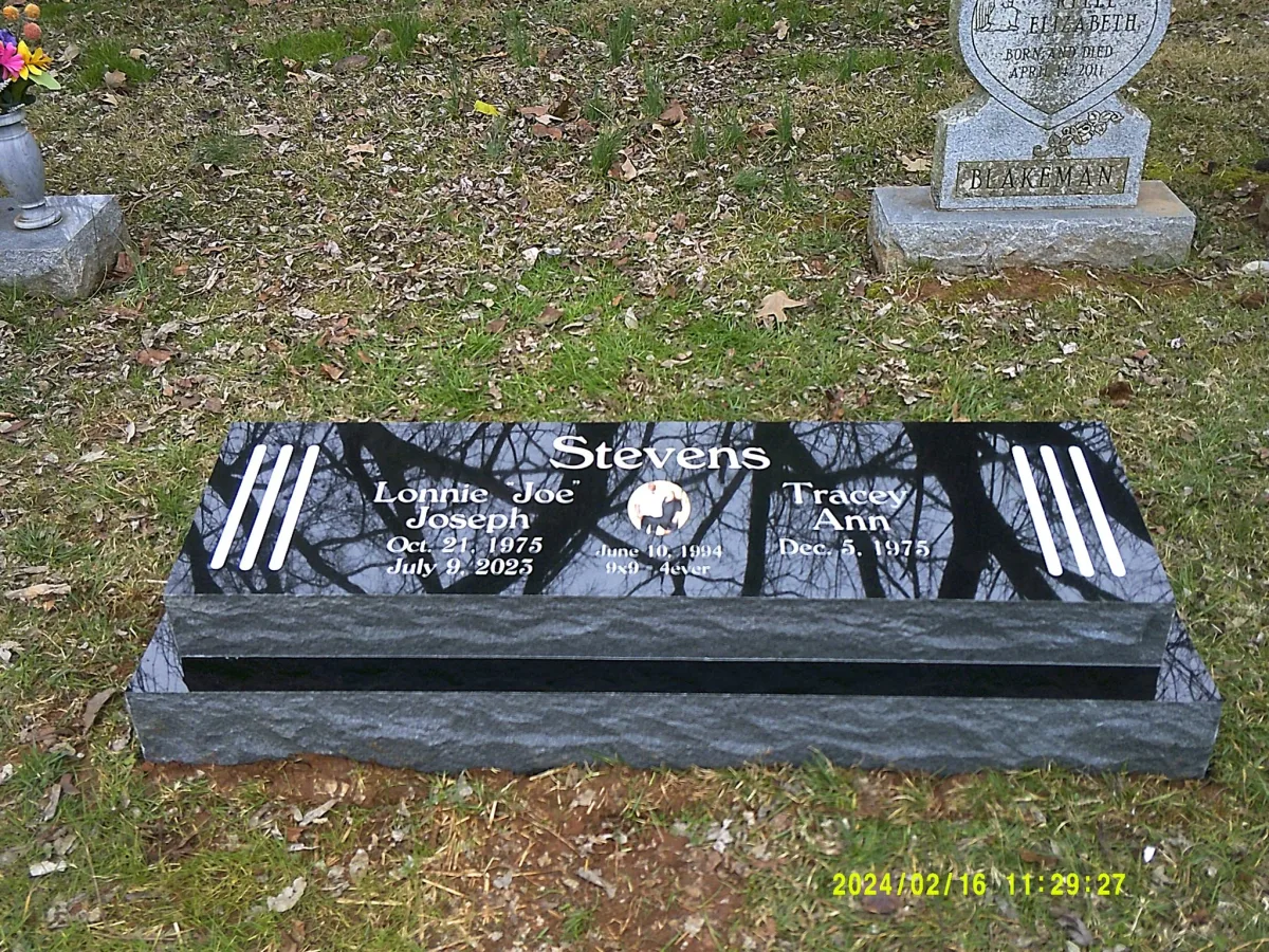 A polished black companion marker reflecting branches, with light lettering and a central emblem