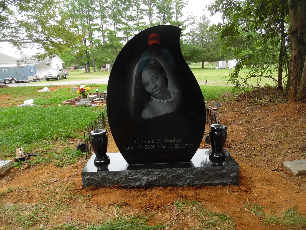 A curved black Booker memorial with a large engraved portrait and two vases