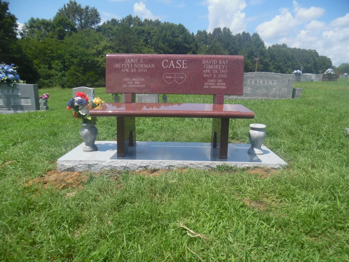 A red granite companion memorial bench with an inscribed backrest