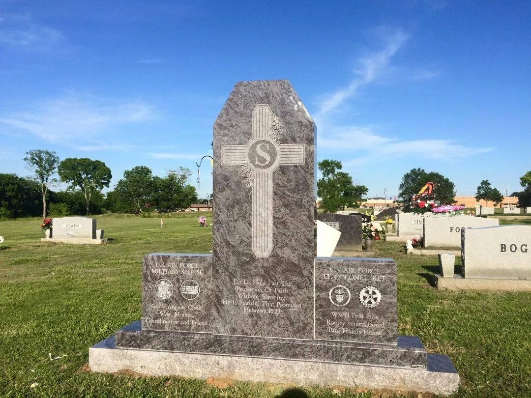 A tall stone memorial with a contrasting cross and two lower inscription panels