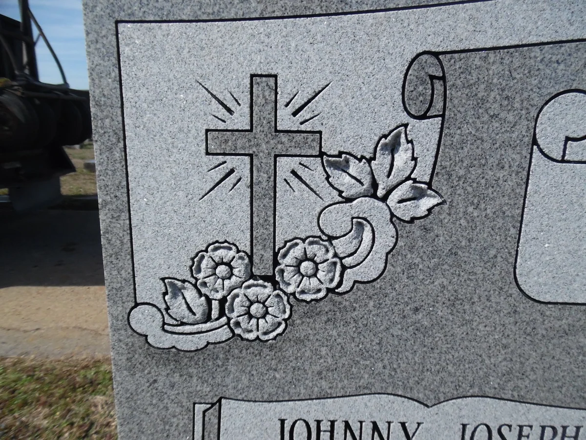Close view of a cross and flowers carved into grey granite