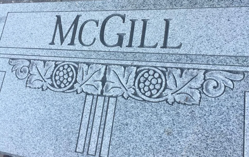 Close view of the McGill name above a carved leaf and floral border