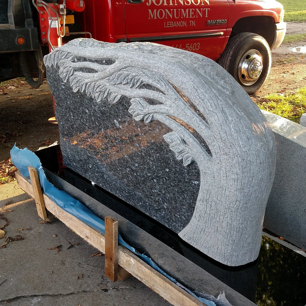 A sculpted branch follows the curved outline of a granite memorial
