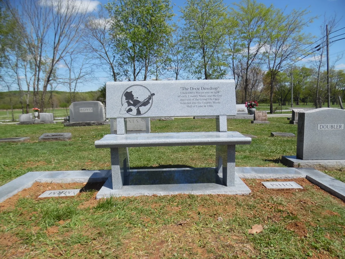 A grey granite memorial bench with an engraved musician and the inscription The Dave Envelope on its backrest