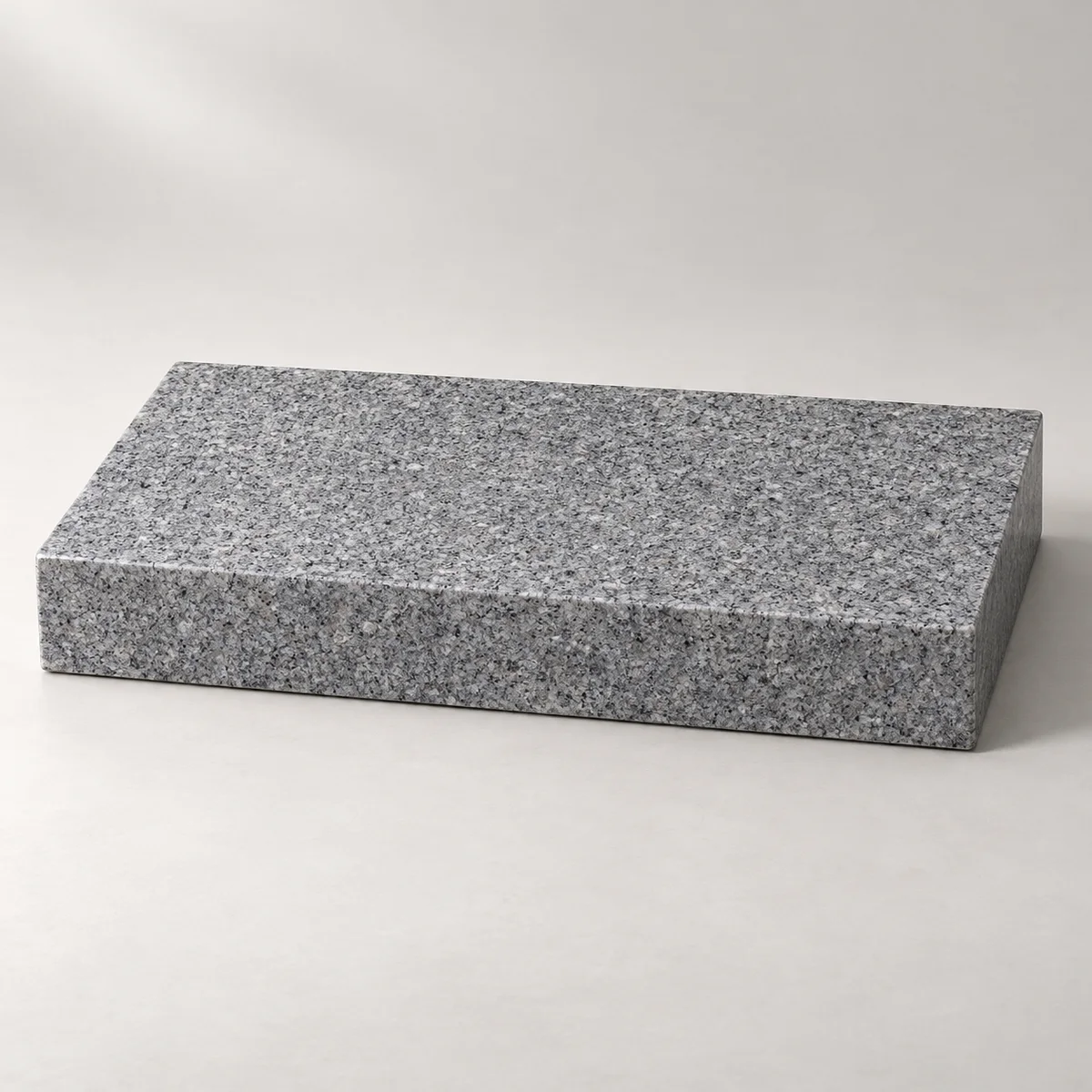 Blank low granite flat marker with a horizontal polished top and straight sawn sides, shown in a studio rather than installed