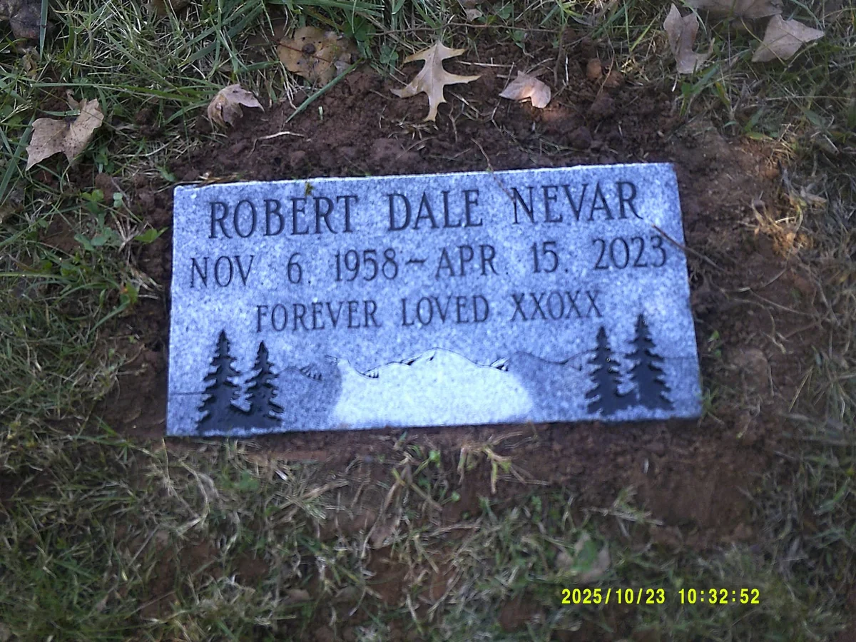 The Nevar flat marker with an engraved mountain landscape and evergreen trees beneath the inscription