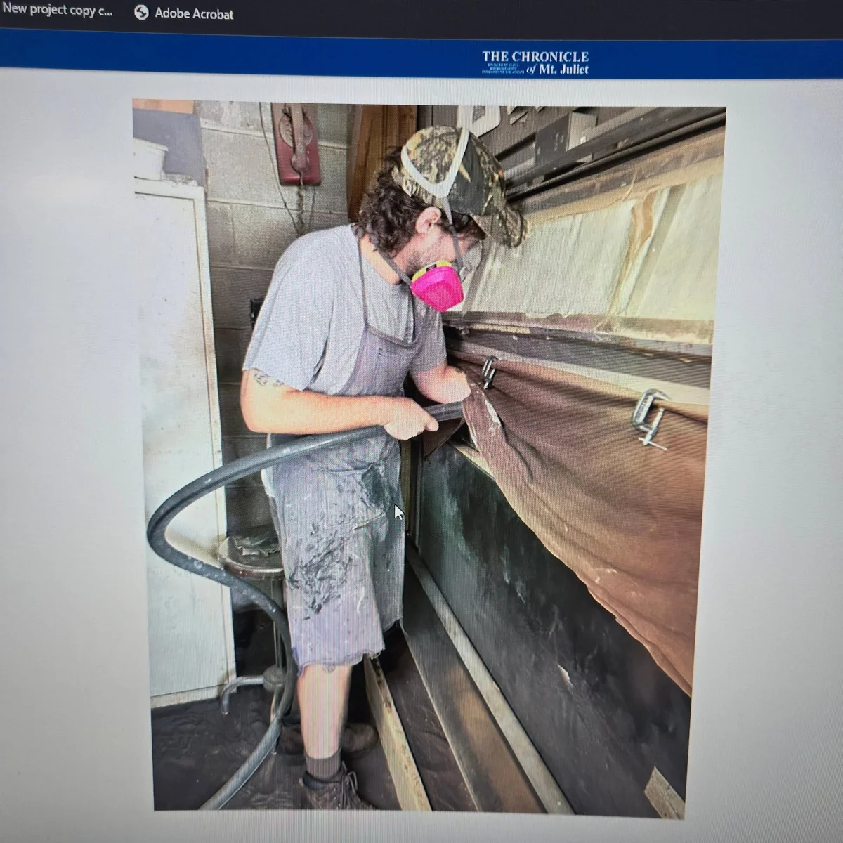Archive newspaper photograph of a worker wearing a respirator and sandblasting at the workshop